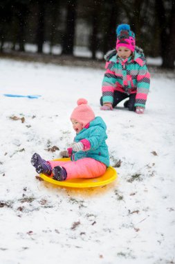 Parlak Kayak takım elbiseli iki kız kardeş kızak kış günü binmek..