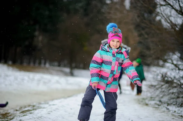 The girl of younger school age spends time in the winter park with pleasure.