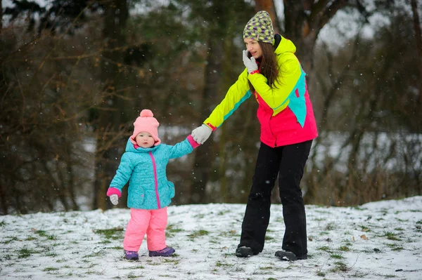 Jovem mãe trouxe a filhinha para o parque de inverno . — Fotografia de Stock