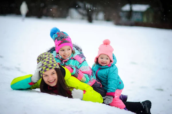 Mladá matka a dvě malé dcery se smířila veselá boj na sněhu. — Stock fotografie