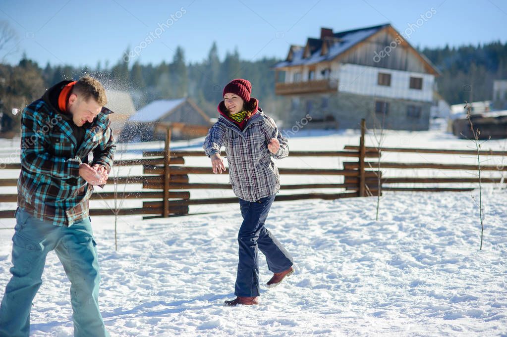 Guy and girl play snowballs.