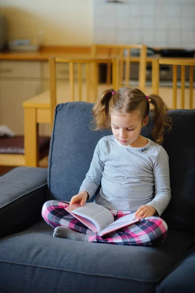 La gentille fille d'âge scolaire plus jeune lit le livre . — Photo