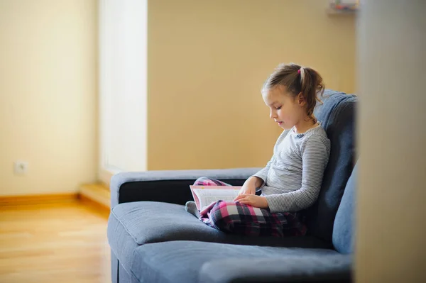 Das nette Mädchen im jüngeren Schulalter liest das Buch. — Stockfoto