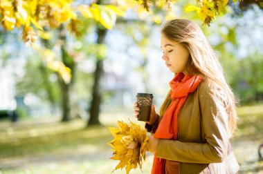Güzel genç kız kahve sonbahar parkta vardır.