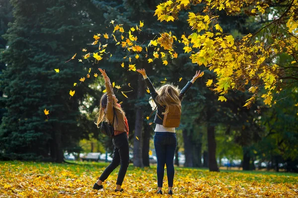 Dojrzały jesień. Dwie dziewczyny wesoły student spacer w parku. — Zdjęcie stockowe