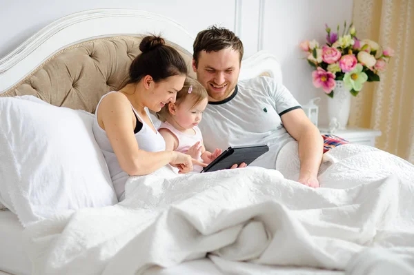 Os pais jovens entretêm a pequena filha . — Fotografia de Stock