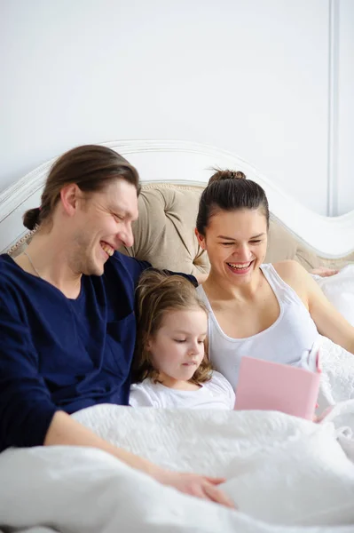 The little daughter reads to parents the book. — Stock Photo, Image