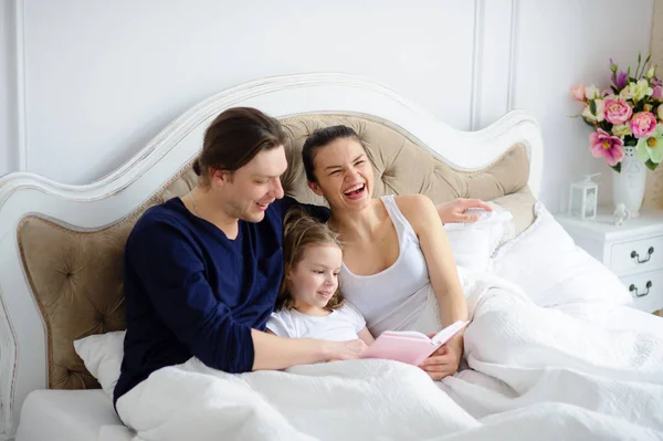 The little daughter reads to parents the book. — Stock Photo, Image