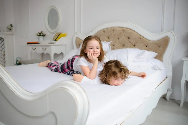 Broer en zus van basisschool leeftijd spelen streken op een bed. — Stockfoto