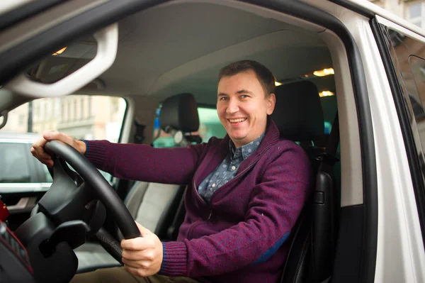 Young man is sitting at the wheel of a car.