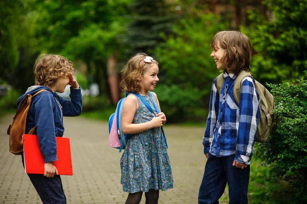 Gli scolari di scuola elementare su qualcosa allegramente parlano sul cortile scolastico . — Foto Stock