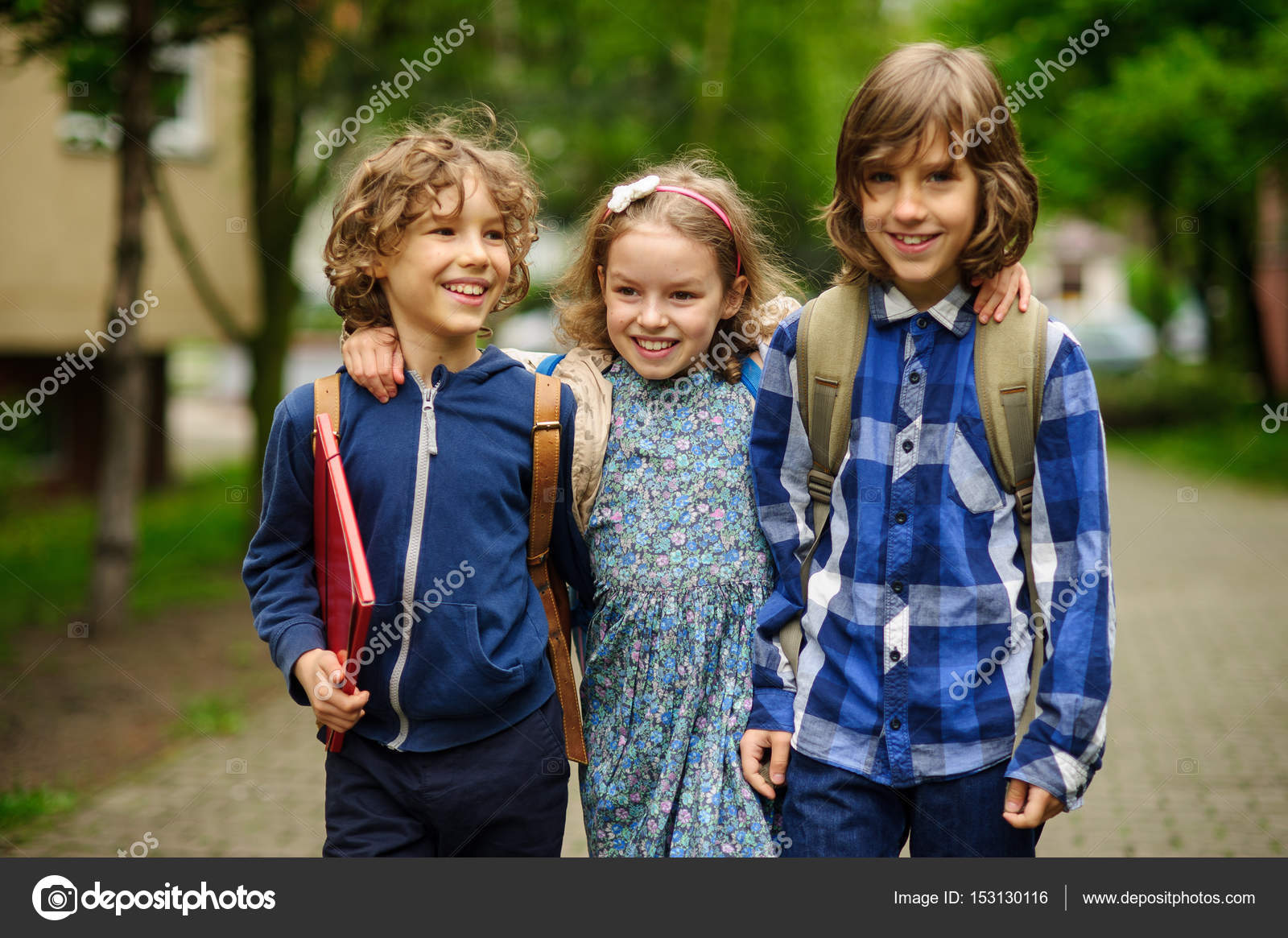 三个小小的学校学生，两个男孩和女孩，站在操场上拥抱. ——图库图片© unguryanu #153130116, image size:1600x1165