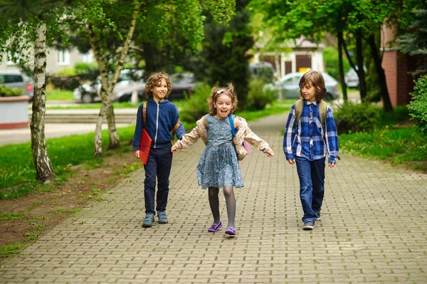 Amüsante kleine Schüler gehen Hand in Hand zur Schule. — Stockfoto