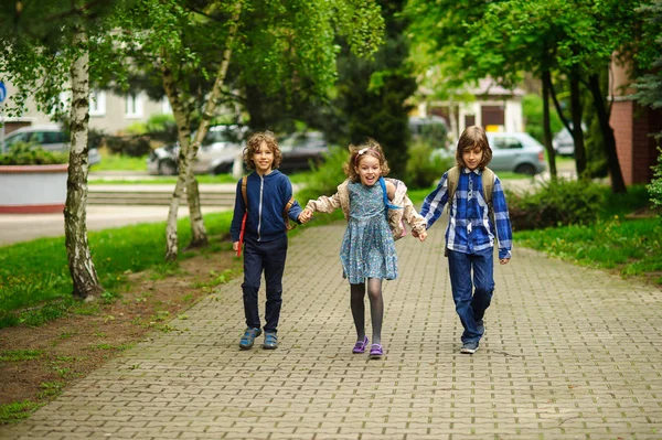 I piccoli studenti scolastici divertenti vanno a scuola avendo unito mani . — Foto Stock