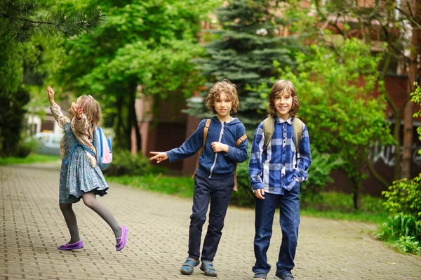 Três amiguinhos apressam-se em lições na escola . — Fotografia de Stock