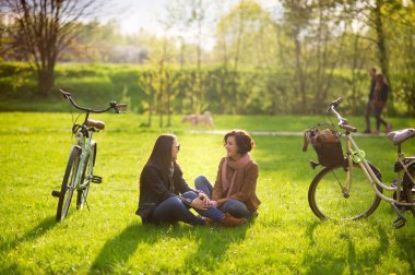 Çekici genç kadın bir yeşil çim bahar parkta oturmak.