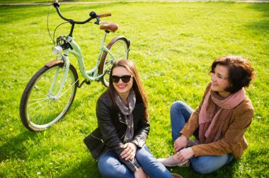 İki genç kadın bir yeşil çimenlerin üzerinde biraz dinlen.