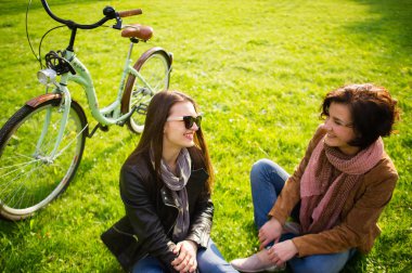 İki genç kadın bir yeşil çimenlerin üzerinde biraz dinlen.