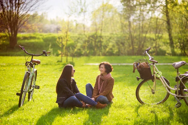 Чарівні молоді жінки сидять на зеленому газоні у весняному парку . — стокове фото