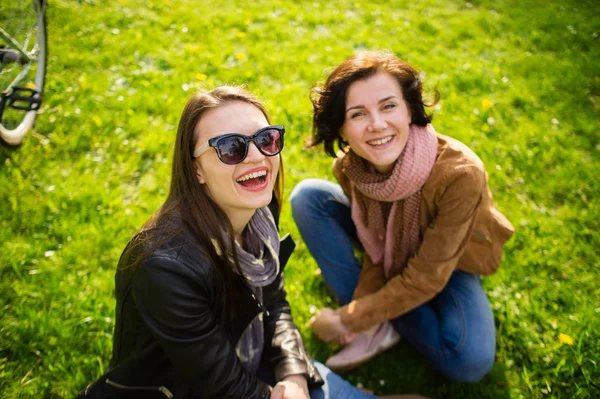 Две молодые женщины отдыхают на зеленой лужайке . — стоковое фото