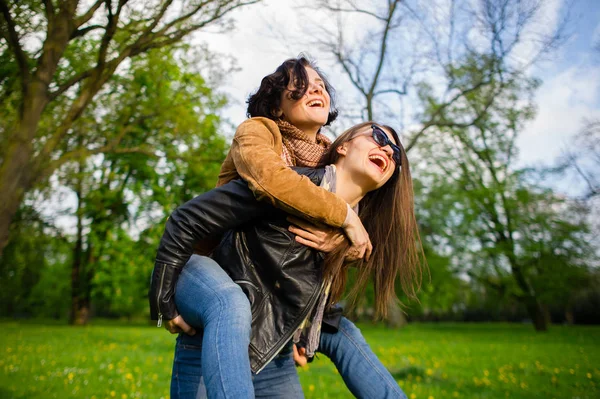 Dos mujeres jóvenes lindas pasan alegremente tiempo en el parque de primavera — Foto de Stock