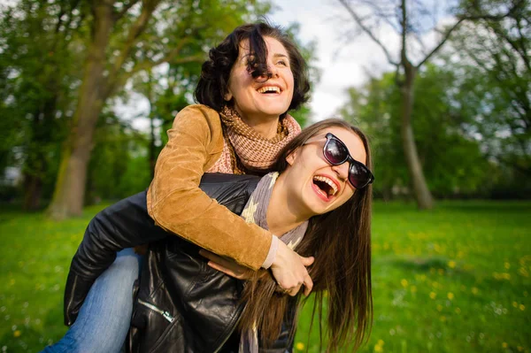 Twee schattige jonge vrouwen doorbrengen vrolijk tijd in het park voorjaarsbijeenkomst — Stockfoto