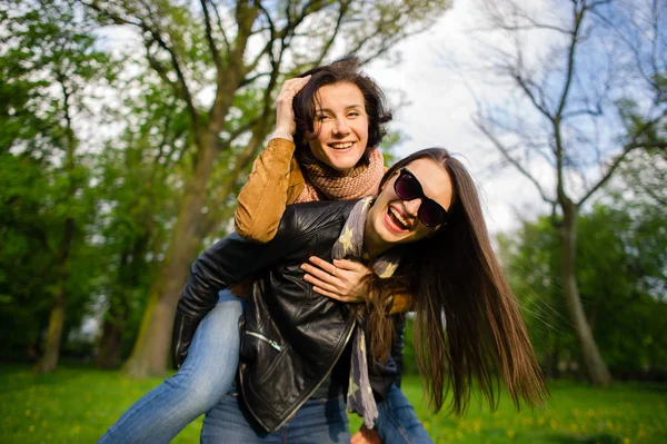 Twee schattige jonge vrouwen doorbrengen vrolijk tijd in het park voorjaarsbijeenkomst — Stockfoto
