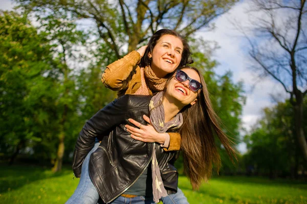 Twee schattige jonge vrouwen doorbrengen vrolijk tijd in het park voorjaarsbijeenkomst — Stockfoto