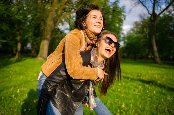 Duas mulheres jovens bonitos alegremente passar o tempo no parque de primavera — Fotografia de Stock
