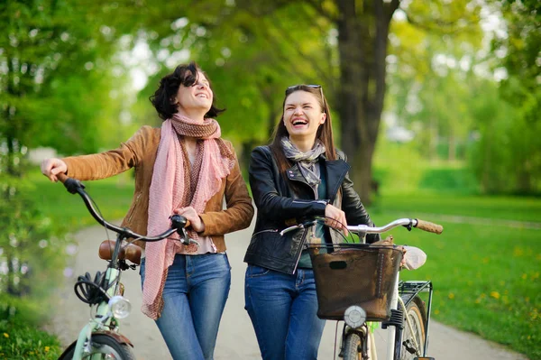 Zwei charmante junge Frauen auf einem Radweg im Frühlingspark. — Stockfoto