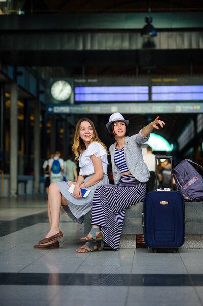 Young women are sitting in the waiting room at the railway station.