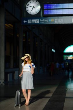 Tren istasyonunun bekleme odasında güneş şapkalı sevimli kız.