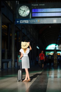 Tren istasyonunun bekleme odasında güneş şapkalı kız.