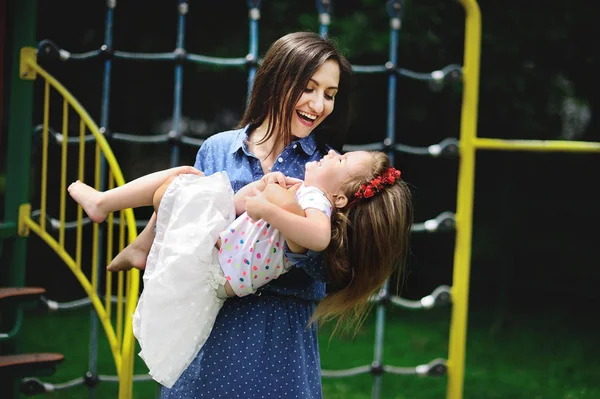 Jonge moeder speelt in de speeltuin met de dochtertje. — Stockfoto