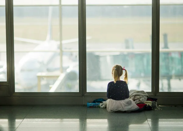Το μικρό κορίτσι να κάθεται κοντά σε ένα μεγάλο παράθυρο στο αεροδρόμιο. — Φωτογραφία Αρχείου