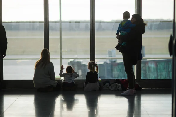 Взрослые и дети сидят у большого окна в аэропорту . — стоковое фото