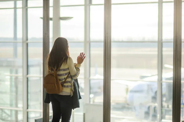 Женщина с рюкзаком стоит у большого окна в аэропорту . — стоковое фото