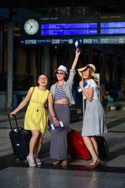 Üç sevimli genç kadın tren istasyonunda.