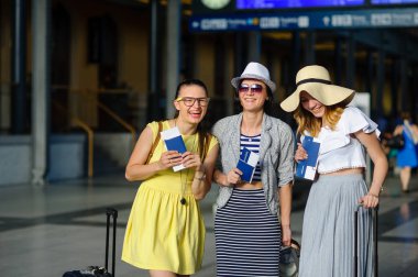 Üç sevimli genç kadın tren istasyonunda.