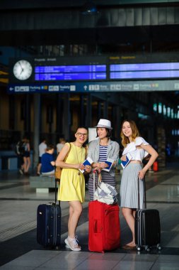 Üç sevimli genç kadın tren istasyonunda.