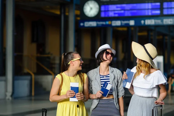 Üç sevimli genç kadın tren istasyonunda.