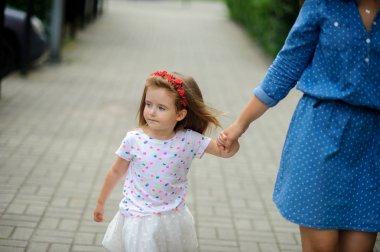 Genç anne parkta küçük kızı ile yürür..