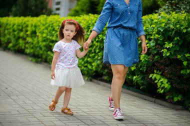 Genç anne parkta küçük kızı ile yürür..