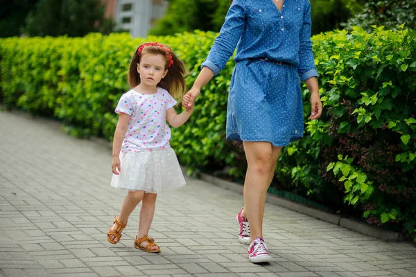 Genç anne parkta küçük kızı ile yürür..