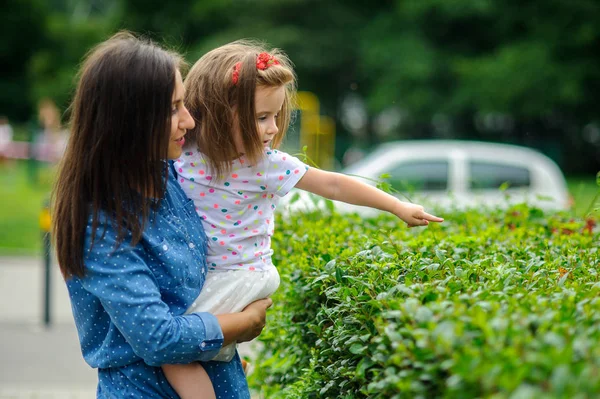 La joven sostiene a la pequeña hija en las manos . — Foto de Stock