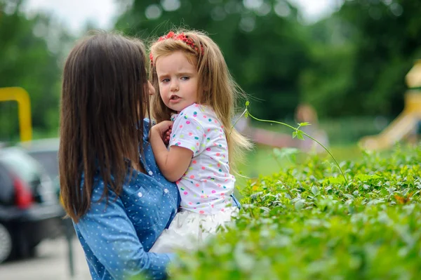 La joven sostiene a la pequeña hija en las manos . — Foto de Stock