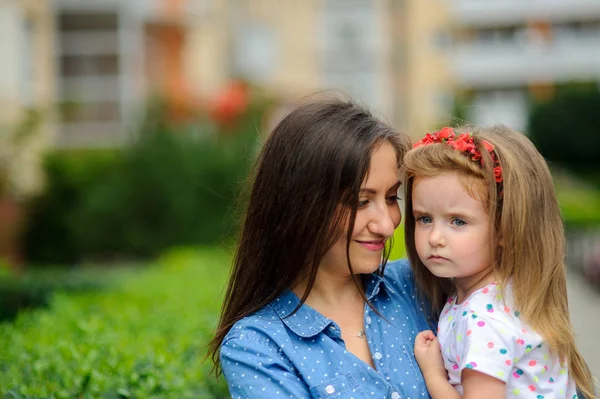 Genç kadın küçük kızı ellerinde tutar..