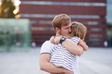 Genç baba küçük kızı ellerinde tutar..