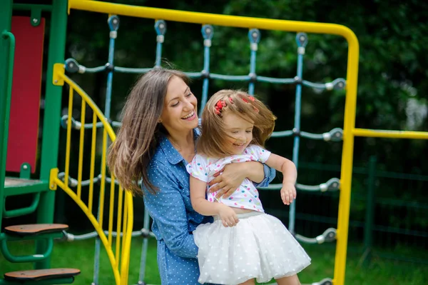 Jonge moeder speelt in de speeltuin met de dochtertje. — Stockfoto