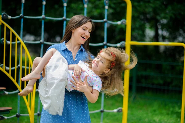 Jonge moeder speelt in de speeltuin met de dochtertje. — Stockfoto